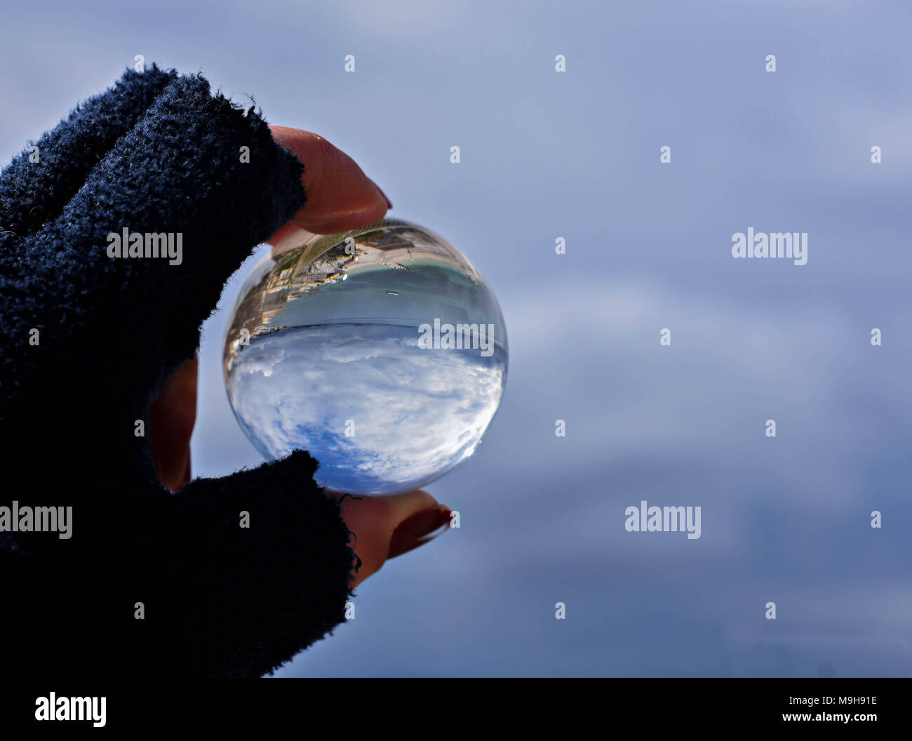 Woman`s hand holding glass ball whit panoramic view of sea and sky/ Concept for environment Stock Photo